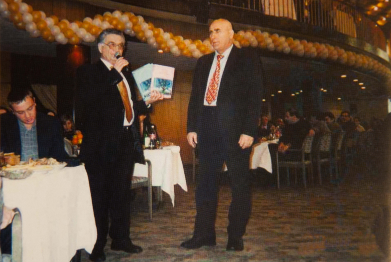  Abhaz soydaşlar toplantısı. Taras Şamba, etkinliğin konuğu Devlet Duma milletvekili Vasily Şandıbin’e “Abhaz şiirinin Antolojisi”ni sunuyor, Moskova, 4 Mart 2002 yılı