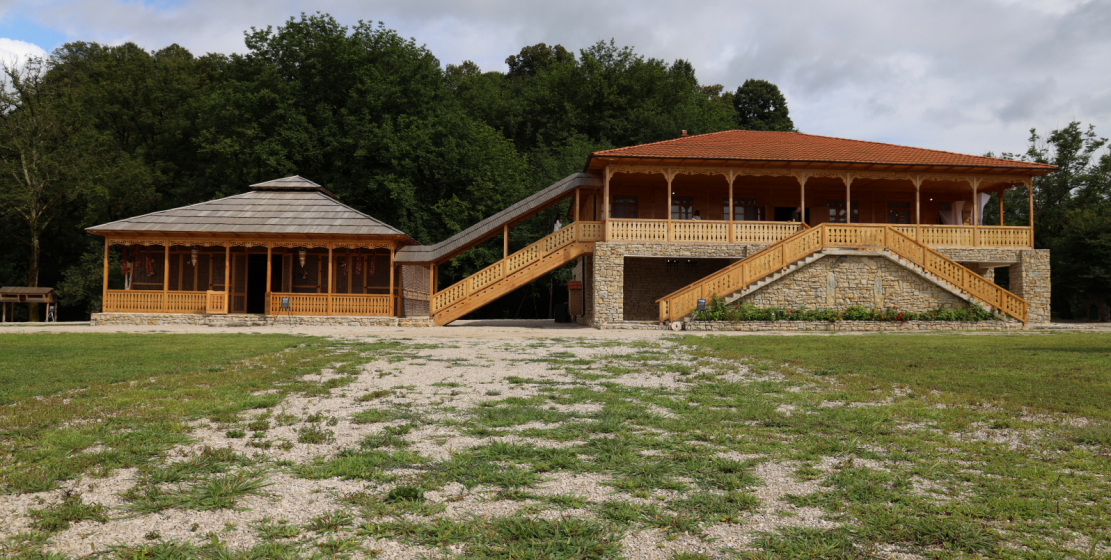 На фото: двор традиционной абхазской усадьбы с ухоженной травой и традиционными абхазскими строениями.